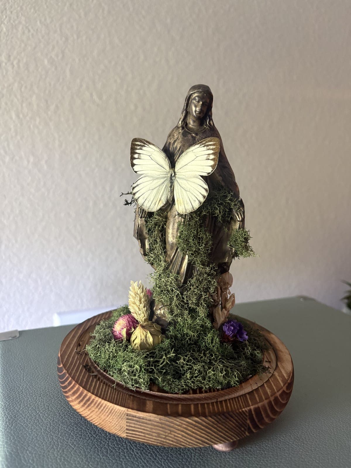 Statue under glass with butterfly and moss